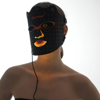 Kvinna som bär Dermao Glow LED-masken inställd på orange ljusterapi