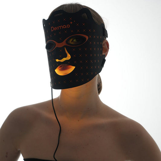 Kvinna som bär Dermao Glow LED-masken inställd på orange ljusterapi