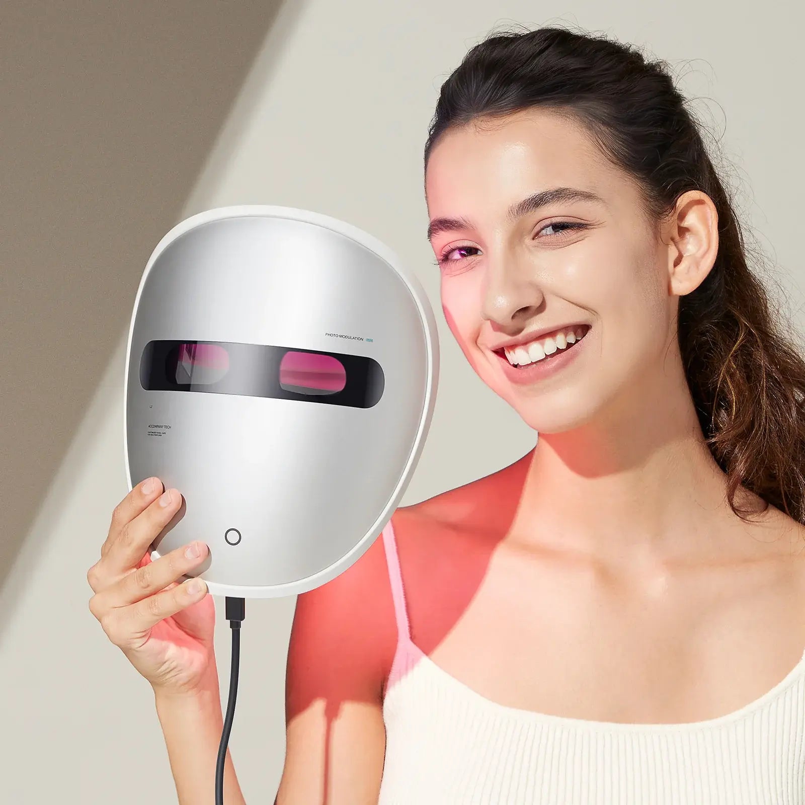 Woman holding Dermao Luxon with red light, smiling against a neutral background