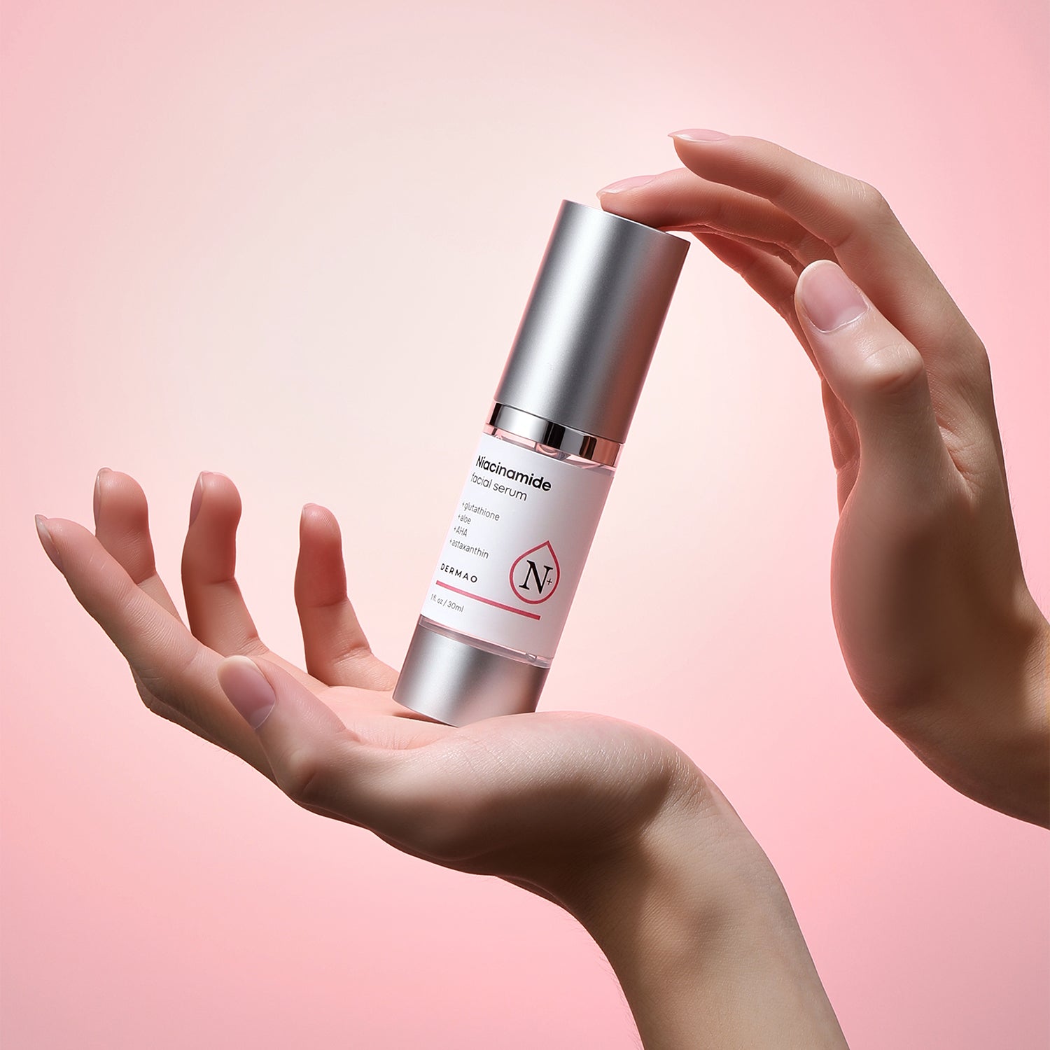 Skincare serum bottle held by a hand against a pink background
